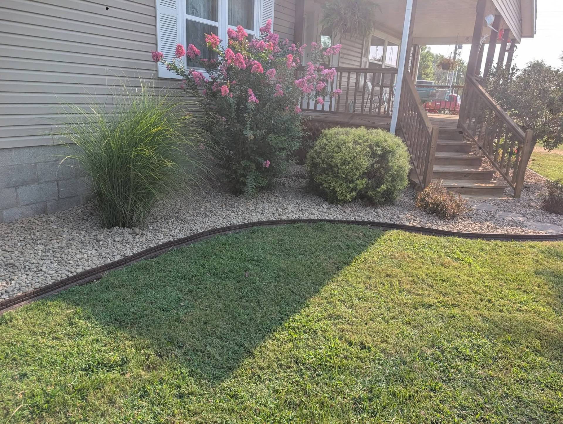 Finished front entry landscape with river rock, mature shrubs, and crisp curved edging