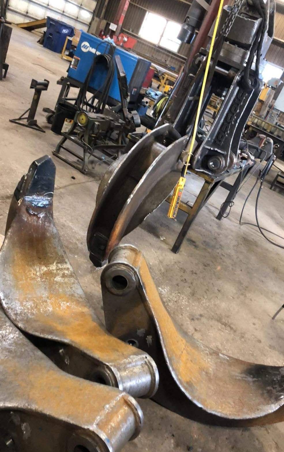 Heavy equipment grapple components laid out in the shop