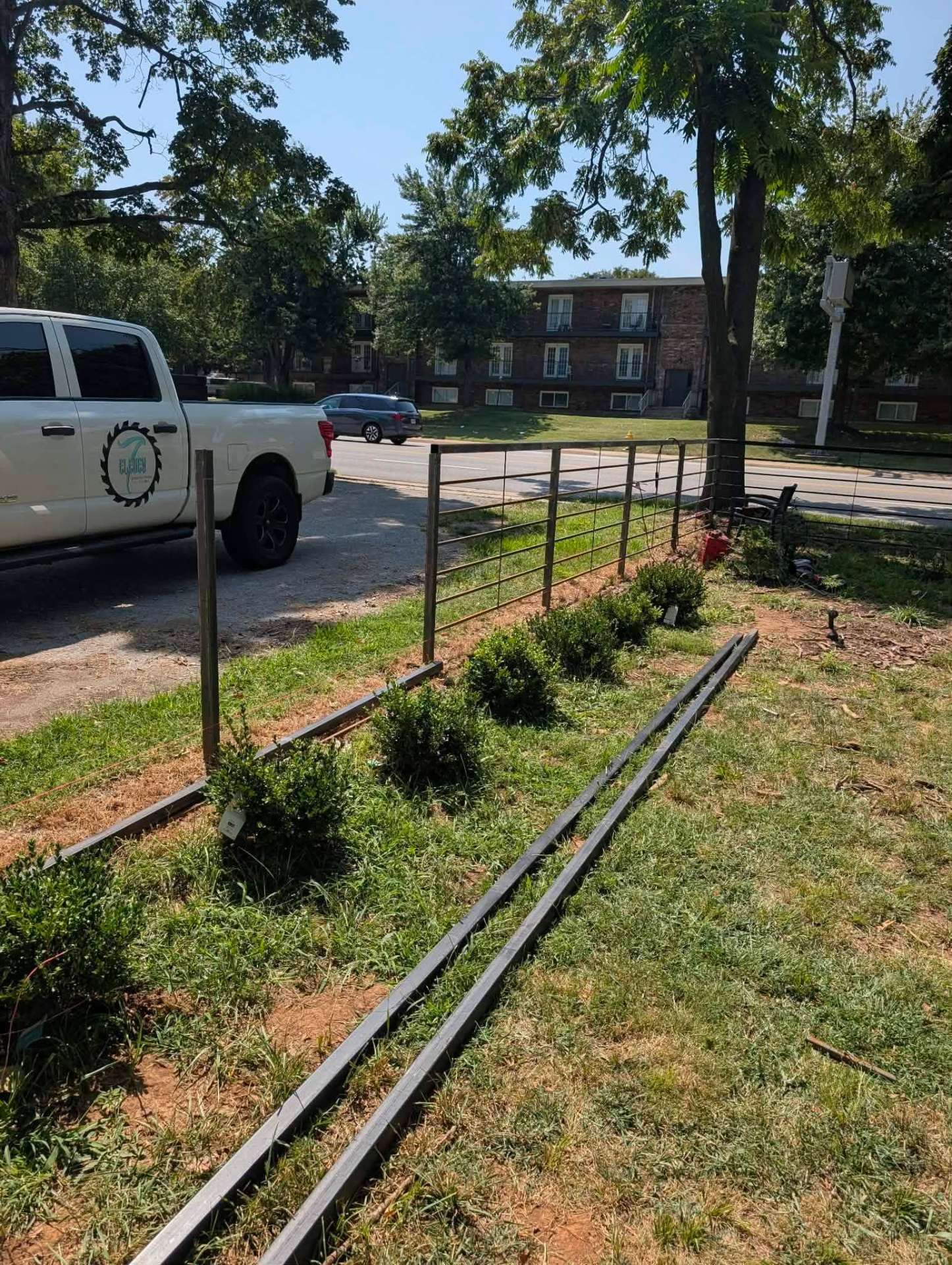 Steel rail fence panels along a grassy property line