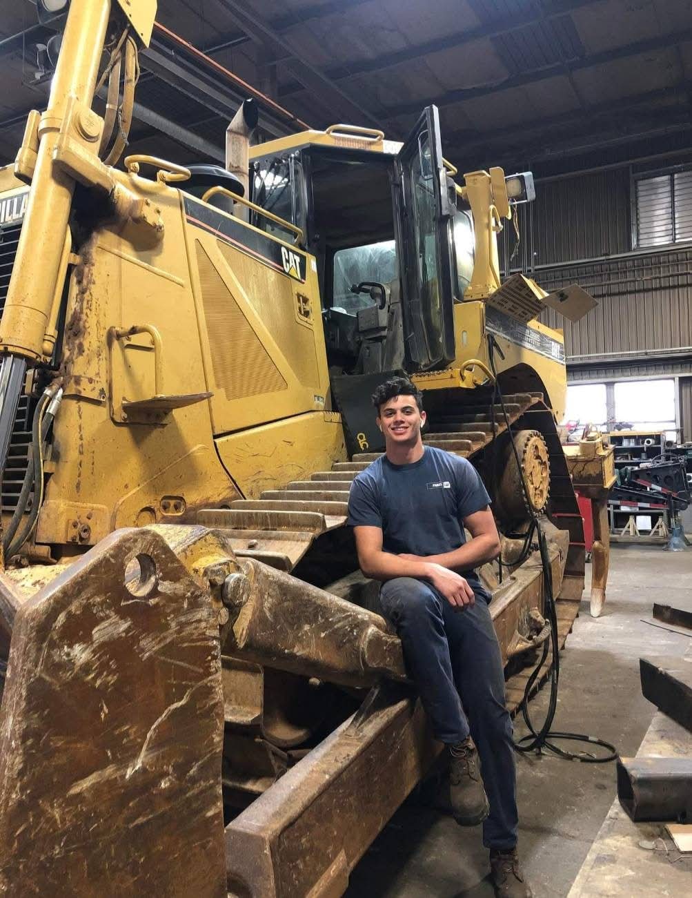 Antonio working beside a Caterpillar dozer in the shop